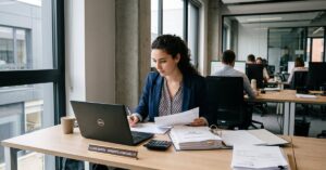 Étudiant en alternance comptabilité travaillant sur des documents financiers dans un bureau moderne